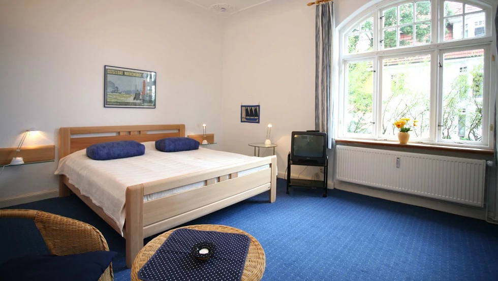 Originalaufnahme des Schlafbereichs der Ferienwohnung mit großen Sprossenfenstern